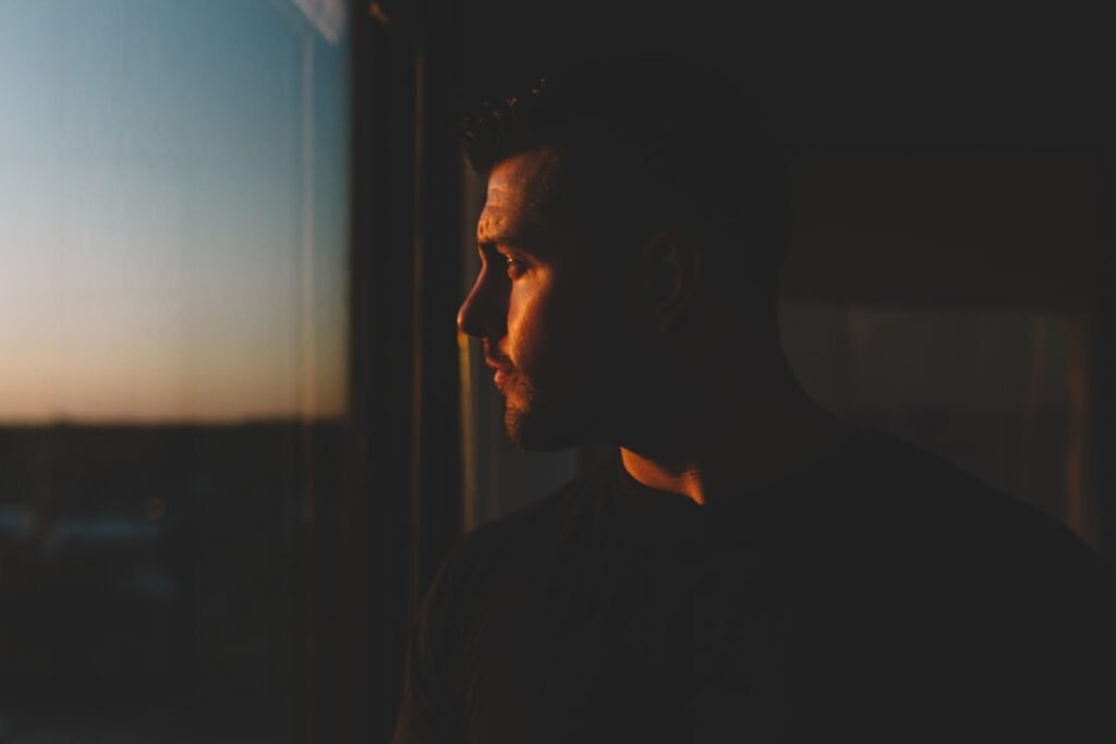 A person sitting quietly by a window in soft morning light, appearing calm and reflective