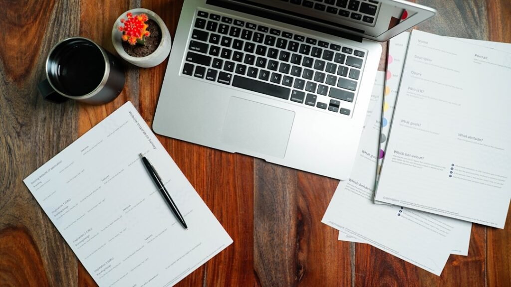 A researcher's desk with printed study papers, charts, and a laptop showing data graphs