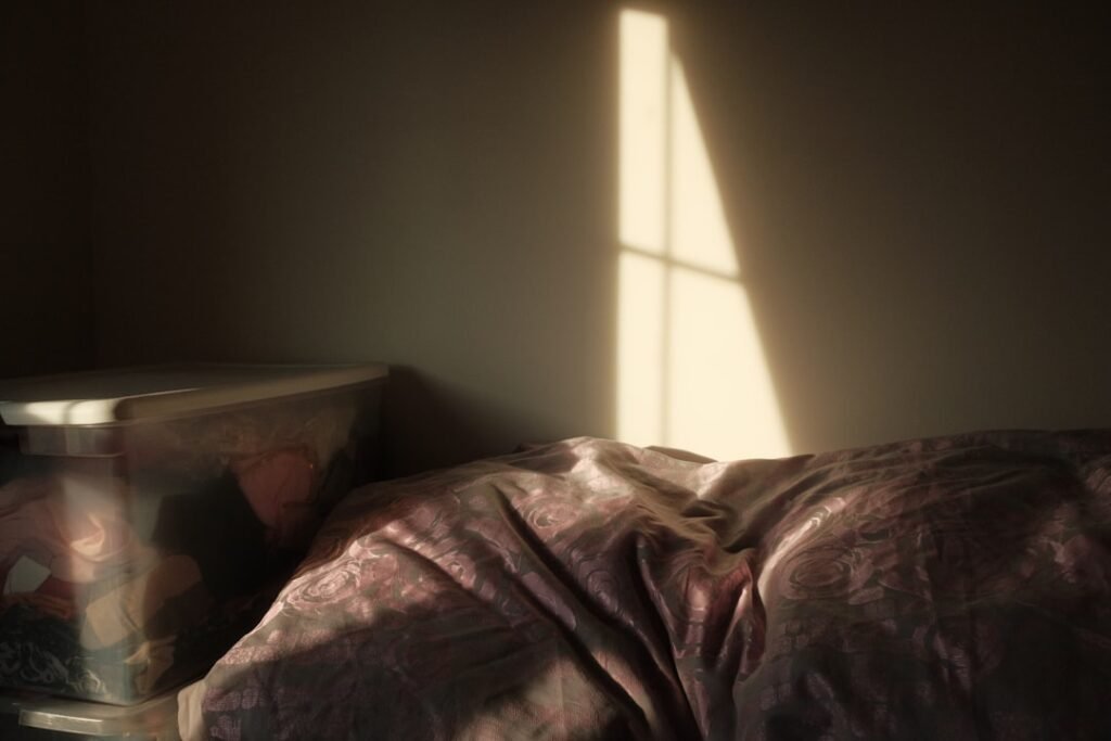 Soft morning sunlight streaming through a window across an unmade bed
