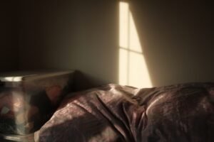 Soft morning sunlight streaming through a window across an unmade bed
