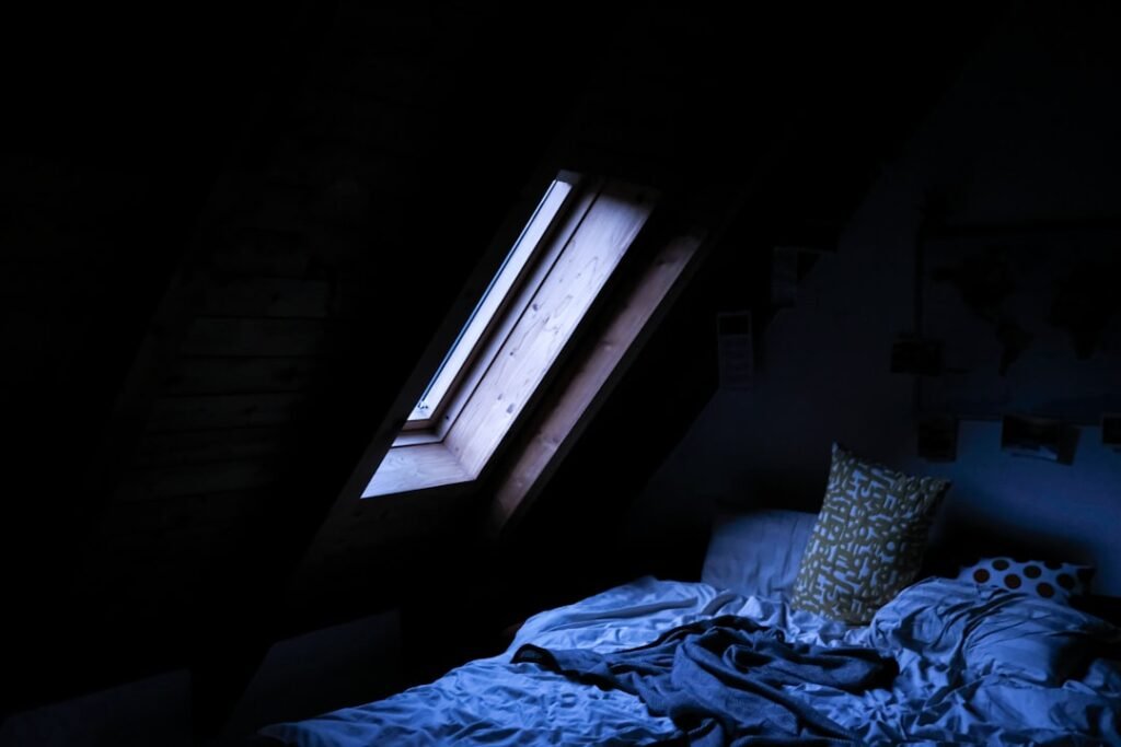 Moonlight falling through a bedroom window onto an empty bed at night
