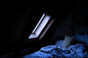 Moonlight falling through a bedroom window onto an empty bed at night