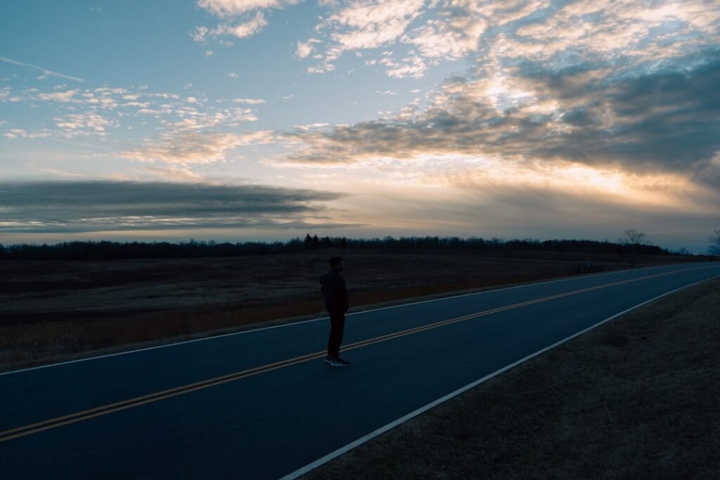 A lone runner moving at a steady, relaxed pace along an open road in early morning light
