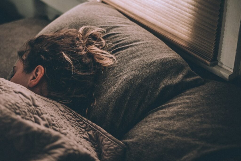 A person asleep in bed with soft natural light coming through a window