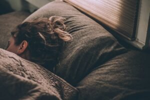 A person asleep in bed with soft natural light coming through a window